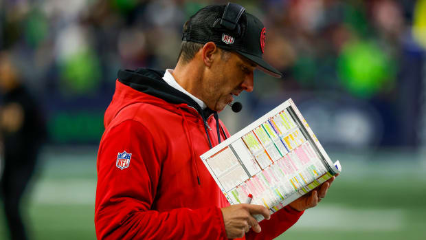San Francisco 49ers head coach Kyle Shanahan stands on the sideline, reading from his playsheet during a game.
